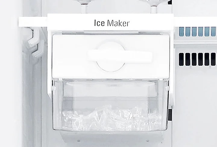 냉장고 내부에 설치된 얼음 제조기가 보입니다. Ice Maker라는 텍스트가 상단에 적혀 있으며, 투명한 용기 안에는 얼음이 담겨 있습니다. 주변은 흰색으로 깔끔하게 마감되어 있습니다.